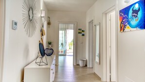 Een gang met houten vloer, een radiator, een wandlamp en een deur naar buiten.