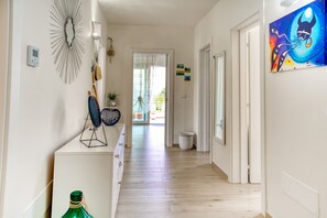 A hallway with a wooden floor, a radiator, a wall-mounted light fixture, and a door leading to an outdoor area. - Cozy house with little pool and sea view (Leuca)
