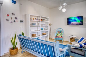 A living room with a blue sofa, a white shelving unit, a television, and a potted plant. - Cozy house with little pool and sea view (Leuca)