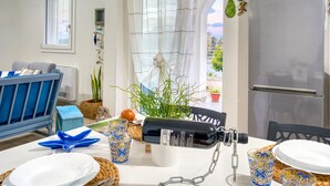 Een eethoek met een tafel gedekt voor twee personen, een koelkast en uitzicht door een raam.
