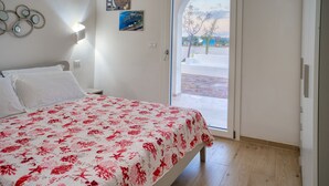 Een slaapkamer met een bed, een deur die naar een balkon leidt en een muur met decoratieve objecten.