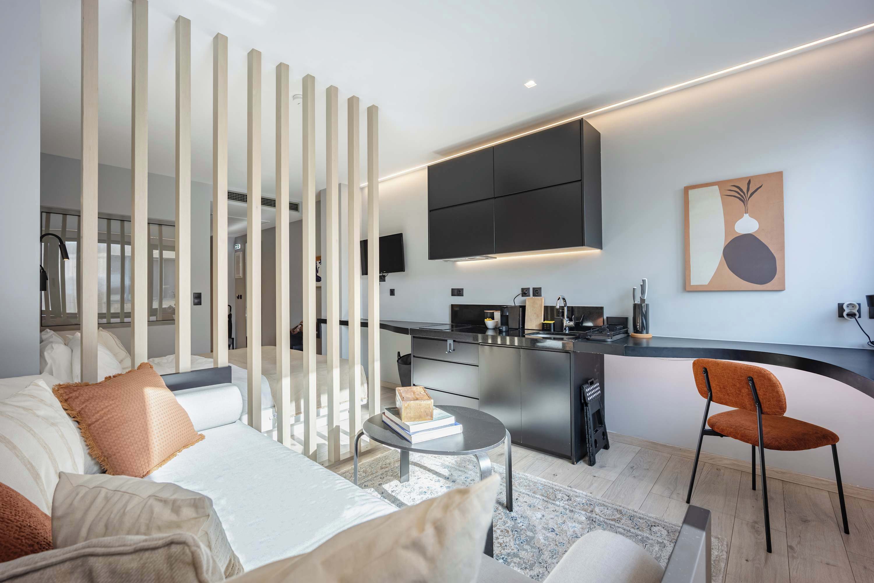 Ein modernes Hotelzimmer mit einer Couch, einem Esstisch, einer Küchenzeile und einem Wandbild.