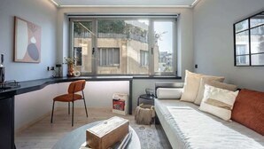 Un dormitorio moderno con un ventanal grande, una cama, un escritorio y una silla.