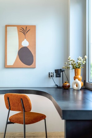 A modern interior with a chair, a vase with flowers, and a painting on the wall. - Cozy Spacious Studio Psyri AcropolisView (Athina)