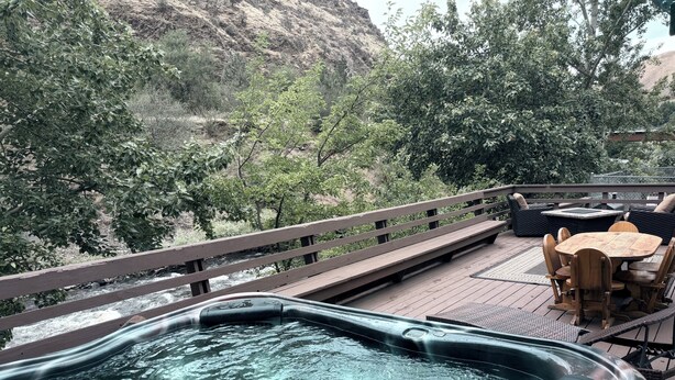 Un bain à remous sur une terrasse en bois, avec vue sur une rivière et les arbres environnants.