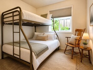 Quarto com beliche, janela, cadeira e abajur.