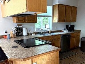 A kitchen with wooden cabinets, granite countertops, a dishwasher, and a window with a view.