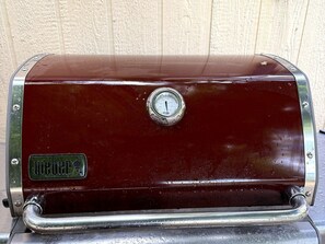 Un barbecue rouge d’époque, de type portable, doté d’un bouton de réglage, d’une marque et d’une poignée.