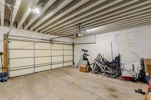 A garage with a closed garage door, concrete floor, and a bicycle parked inside.