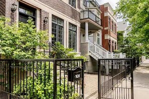 A residential building with a brick facade, a gated entrance, and a visible mailbox. - Huge Lakeview Retreat near Wrigley Field with mutliple balconies (Chicago)