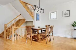 A dining area with a wooden staircase, a chandelier, and framed pictures on the wall. - Huge Lakeview Retreat near Wrigley Field with mutliple balconies (Chicago)