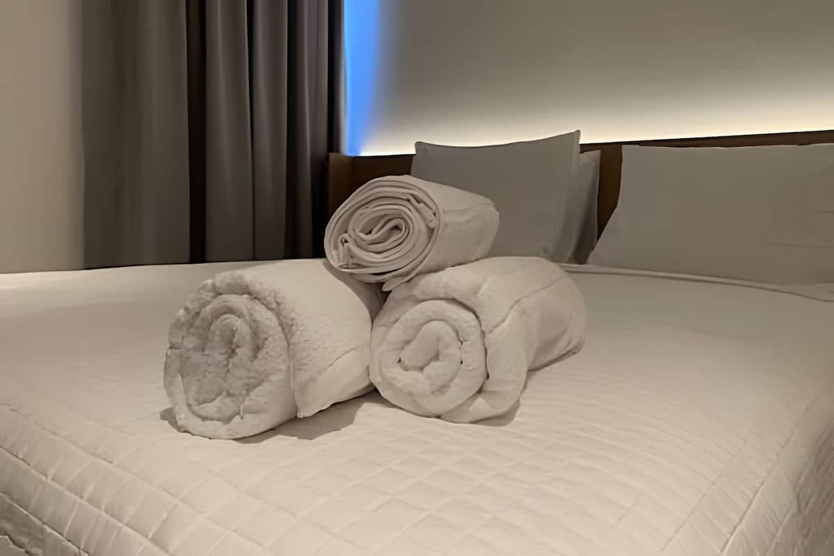 Un lit avec des serviettes blanches roulées et une tête de lit.