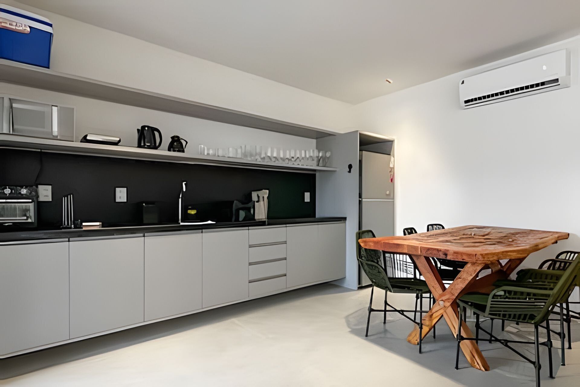 Una cocina moderna con armarios grises, una mesa de comedor de madera y una cafetera.