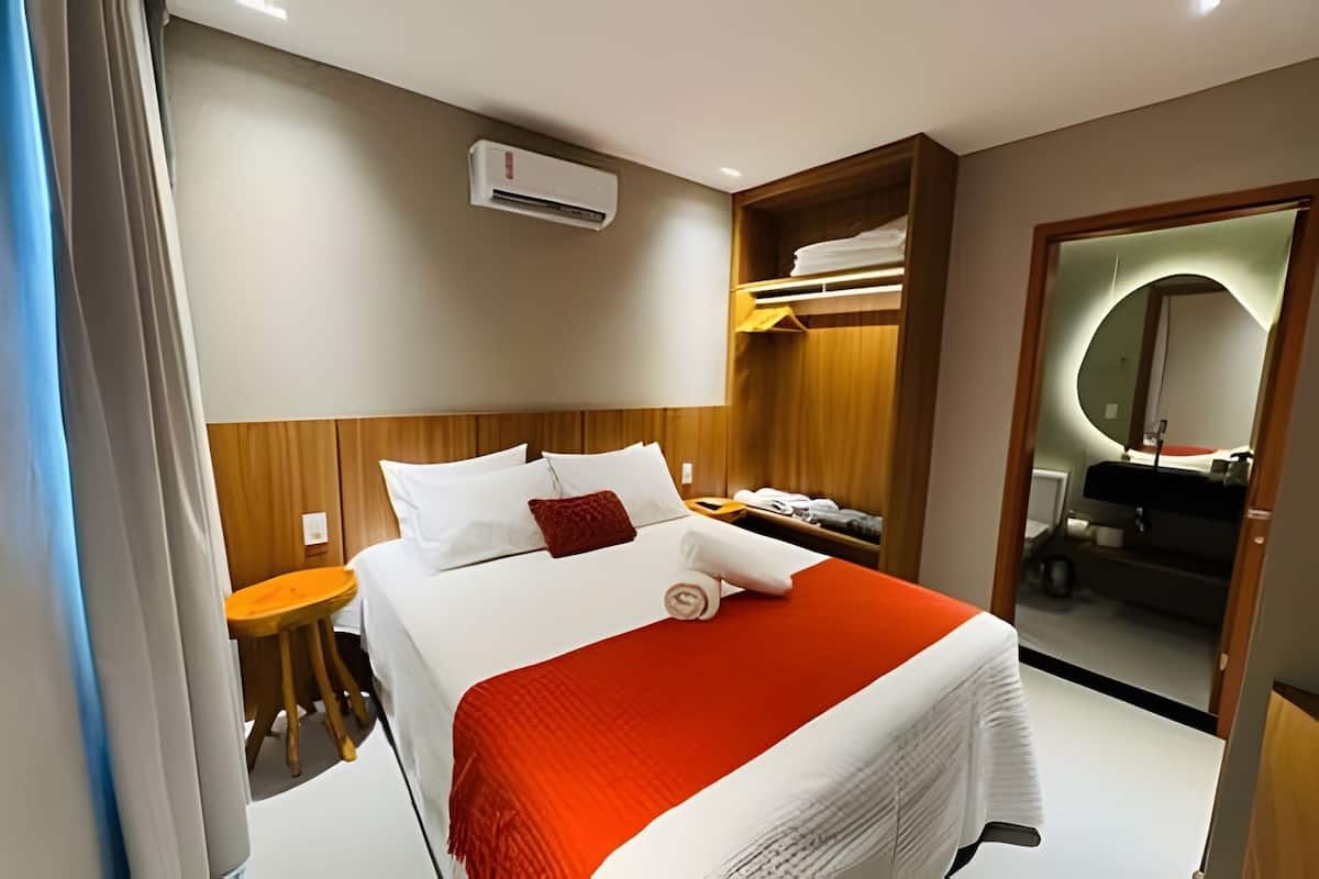 Une chambre d’hôtel avec un lit, une petite table, une armoire et un miroir.