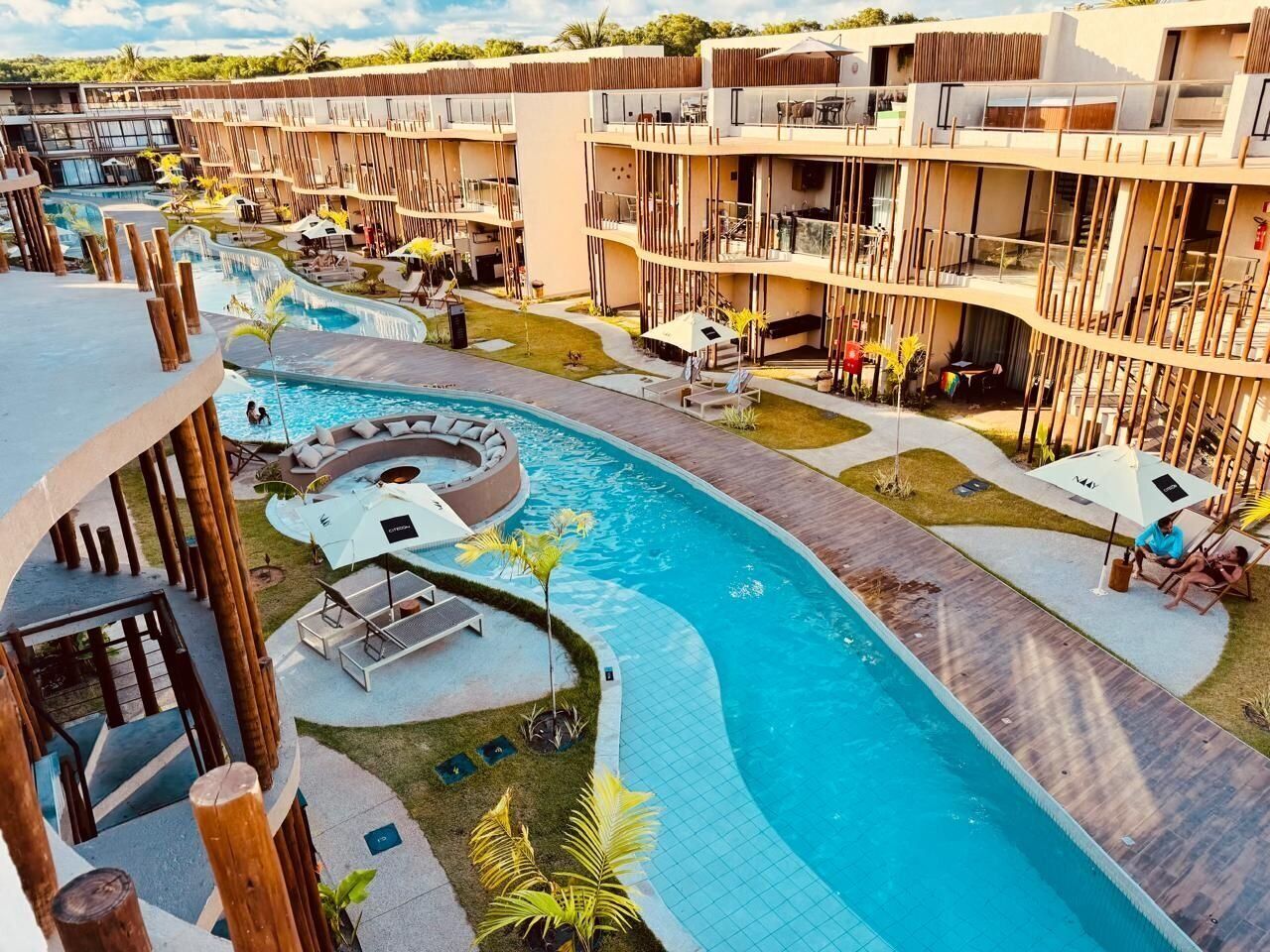 A resort with a swimming pool, outdoor seating, and multiple-story buildings.