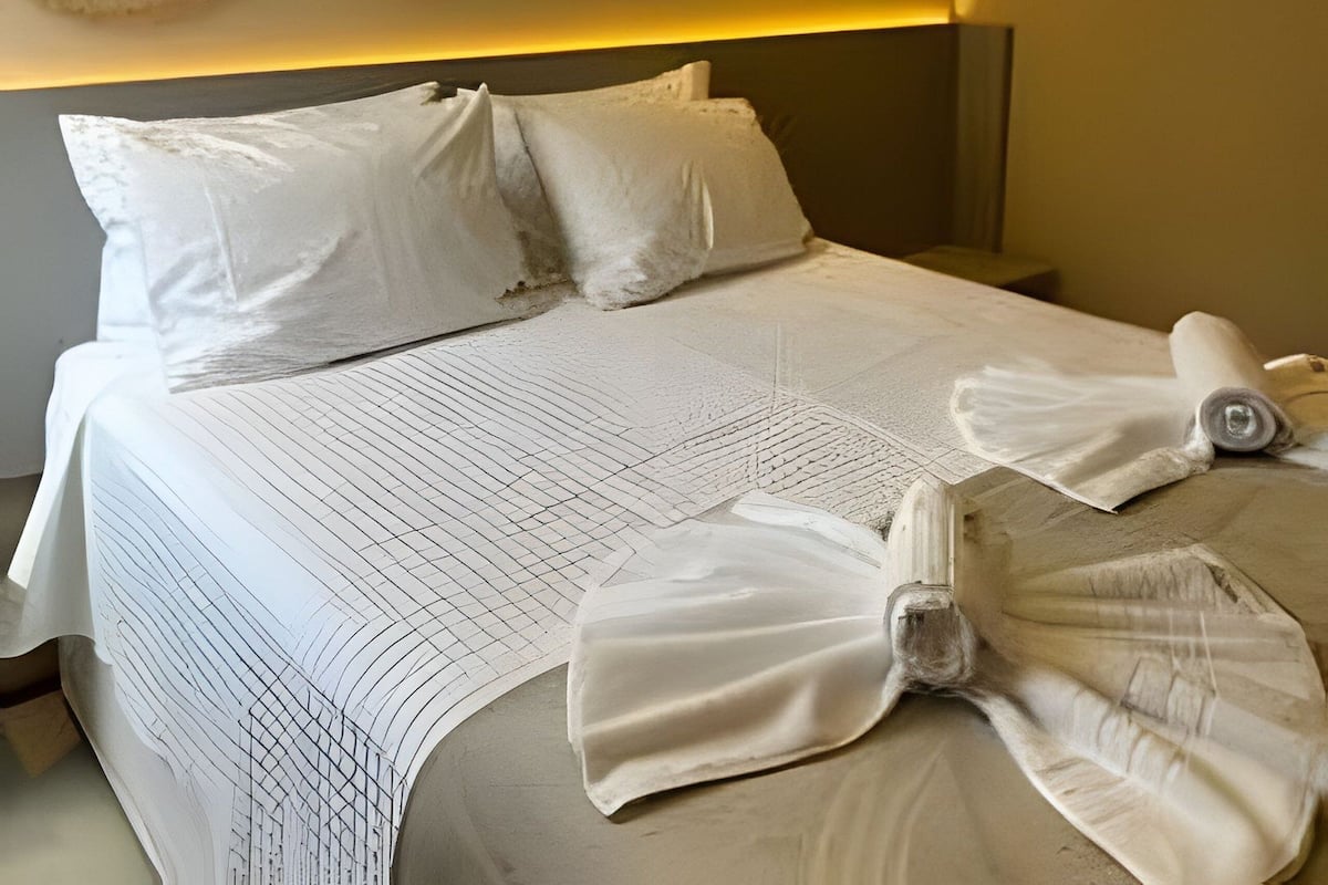 Une chambre d’hôtel avec un lit, des oreillers, une couverture et un climatiseur fixé au mur.