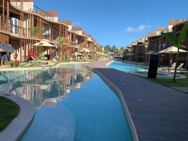 A resort with a swimming pool, wooden balconies, and lounge chairs.
