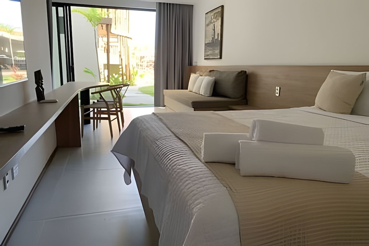 Quarto de hotel com cama, sofá, escrivaninha e cadeira.