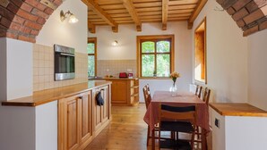 Eine Küche mit Holzschränken, einem eingebauten Ofen und einem Essbereich mit kariertem Tischläufer.