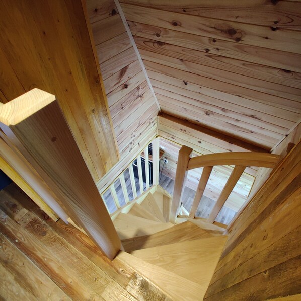 A wooden staircase with a handrail leading to a landing. - Enjoy the sounds of nature when you stay in this unique wooden Tipi. (Vivy)