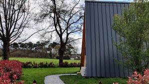 A pathway leading to a building with a metal exterior, surrounded by greenery and trees.