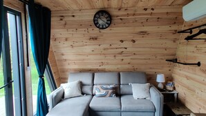 A cozy cabin interior with a sofa, a clock, and a window with curtains.