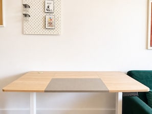 Ein Zimmer mit einem Holztisch, einer Wäschewand mit Bildern und einem grünen Sofa.