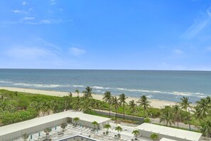 Ein Hotel mit Pool auf dem Dach, Palmen und Blick auf Strand und Meer.