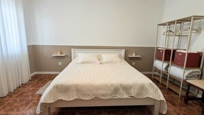Ein Schlafzimmer mit einem Bett, einem Nachttisch, einem Kleiderschrank und einem Fenster mit Vorhängen.