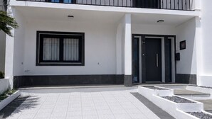 Ein zweistöckiges Gebäude mit flachem Dach und einem Balkon im oberen Stockwerk, mit einer Tür, die die Nummer 154 trägt.