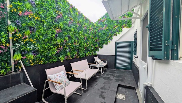 Eine Dachterrasse mit grüner Wand, Sitzgelegenheit und einer Treppe.