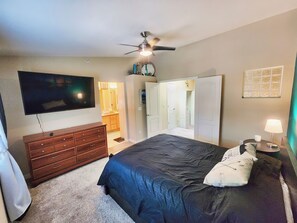 A bedroom with a bed, dresser, TV, ceiling fan, and a walk-in closet. - Broadmoor Retreat Mtn Views Hiking and Biking (Colorado Springs)