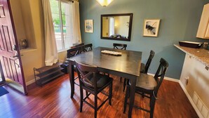 Un coin repas avec une table et des chaises en bois, un lustre et un grand miroir au mur.