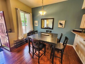 A dining area with a wooden table and chairs, a chandelier, and a large mirror on the wall. - Broadmoor Retreat Mtn Views Hiking and Biking (Colorado Springs)