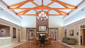 A spacious lobby with a high ceiling, wooden beams, a chandelier, a fireplace, and a reception desk. - Myrtle Beach Family Escape with Spacious 3BR Lockoff Resort Suite (Myrtle Beach)