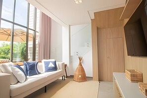 Een moderne woonkamer met een bank, een houten kast en een groot raam.