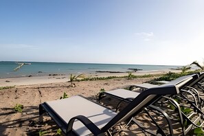Une plage avec des chaises longues et une vue dégagée sur l’océan.