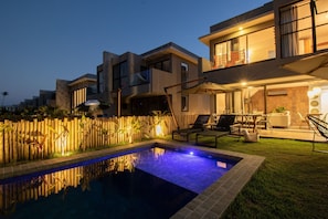 Une maison moderne dotée d’une piscine, de mobilier d’extérieur et d’une clôture en bois.