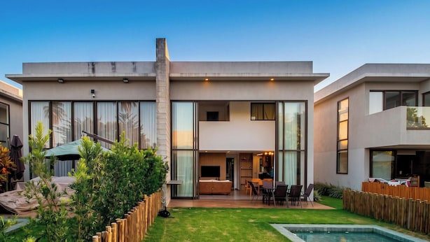 A modern two-story house with a large glass facade, a swimming pool, and a well-maintained garden. - Oka Milagres Cond. Beira Mar By MME (Passo de Camaragibe)