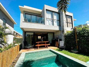 Ein modernes, zweistöckiges Haus mit Pool, Sitzgelegenheit im Freien und einem gepflegten Garten.