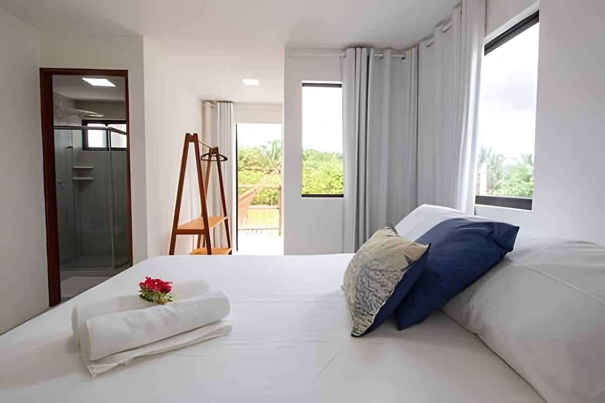 Ein Schlafzimmer mit einem Bett, einem Holzstuhl, einem Fenster und einer Tür.