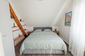 Ein Schlafzimmer mit einem Bett, Holzregalen, einem Nachttisch, einer Wandleuchte und einem gerahmten Bild.
