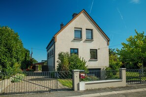 Ein zweistöckiges Haus mit einem geneigten Dach, einem Vorgatter und einem kleinen Garten.