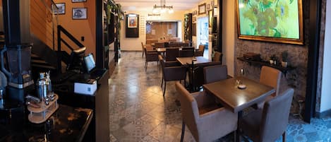 A restaurant with a bar area, dining tables, chairs, and a large framed painting on the wall.