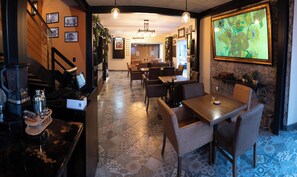 Un restaurant doté d’un bar, de tables, de chaises et d’un grand tableau encadré accroché au mur.