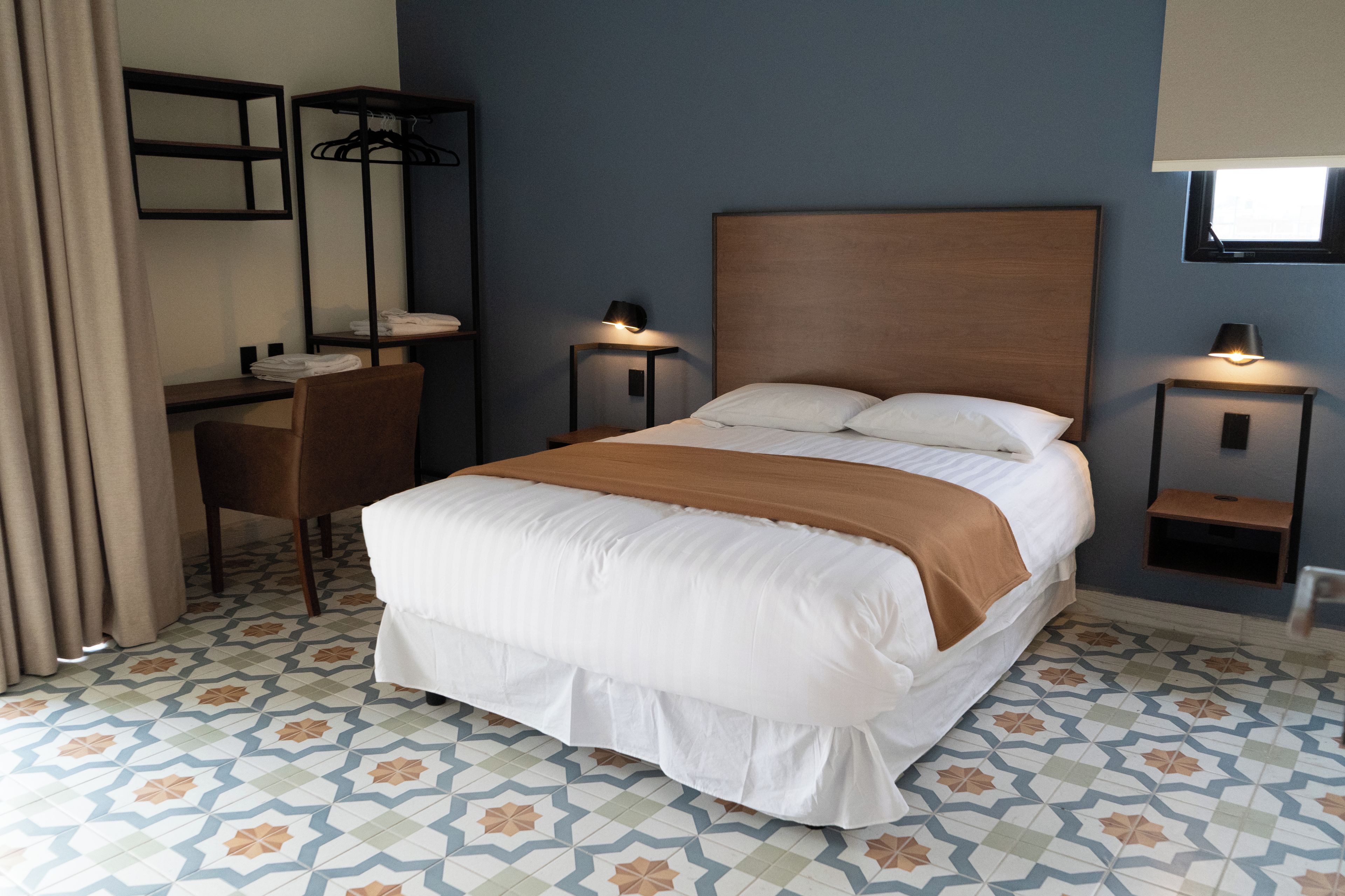 A hotel room with a bed, bedside tables, a desk, and a chair.
