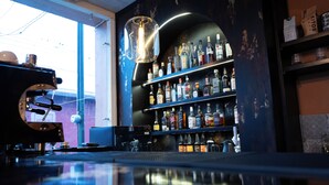 Een bar met flessenkast, een koffieapparaat en een grote lamp.