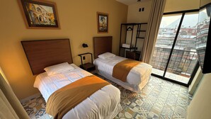 Een hotelkamer met twee bedden, een raam met uitzicht en een schilderij aan de muur.