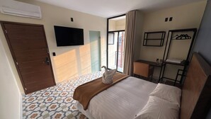 Een hotelkamer met een bed, een bureau, een stoel, een televisie en een raam met gordijnen.