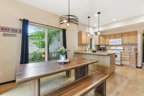 A modern kitchen with wooden cabinets, a central island, and a dining area with benches.